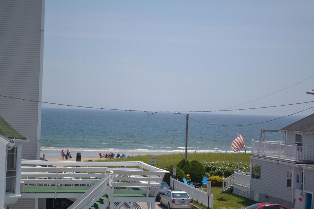 A beachfront view of the Oceanic Inn, with a white railing and an American flag, overlooking the ocean.
