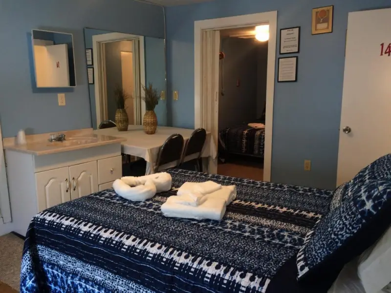 A hotel room with a bed, sink, and table.