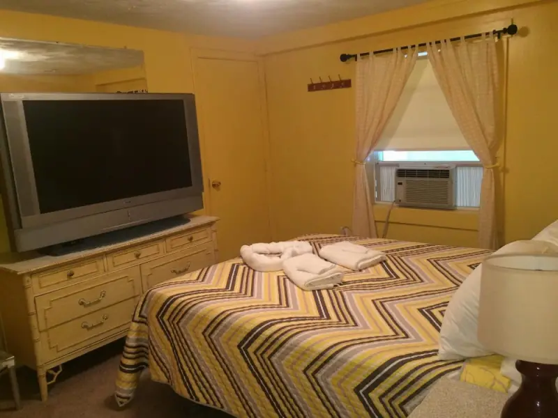 A hotel room with a bed, TV, and dresser