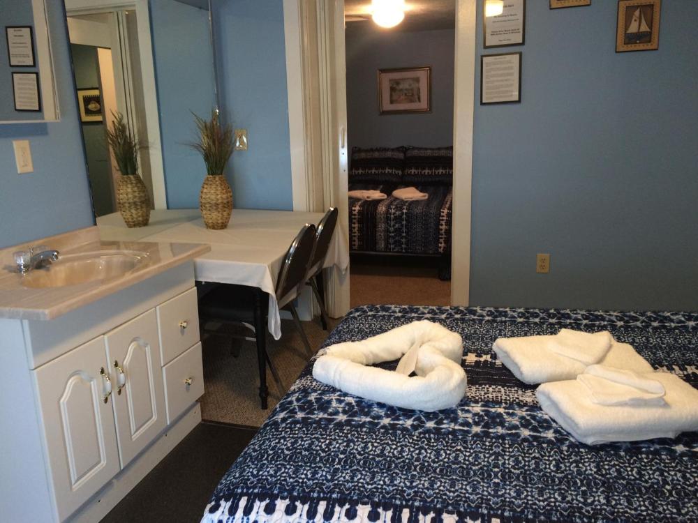A hotel room with a sink, mirror, desk, and bed