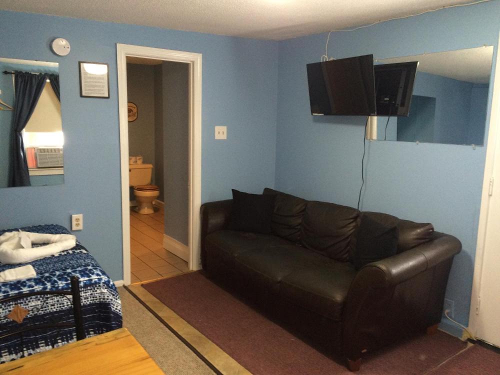 A wide view of a guest room with a bed, couch, TV, and doorway to the bathroom.